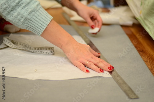 Top view of tailor hands working with scissor and suit textile cloth. Brown suit fabric made of natural wool