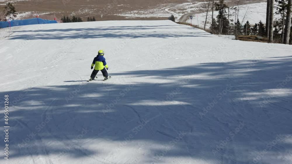 Cute toddler child in colorful ski wear, skiing in Italy on a sunny day, kids and adults skiing together. Family vacation Cute toddler child in colorful ski wear, skiing in Italy on a sunny day, kids and adults skiing together. Family vacation