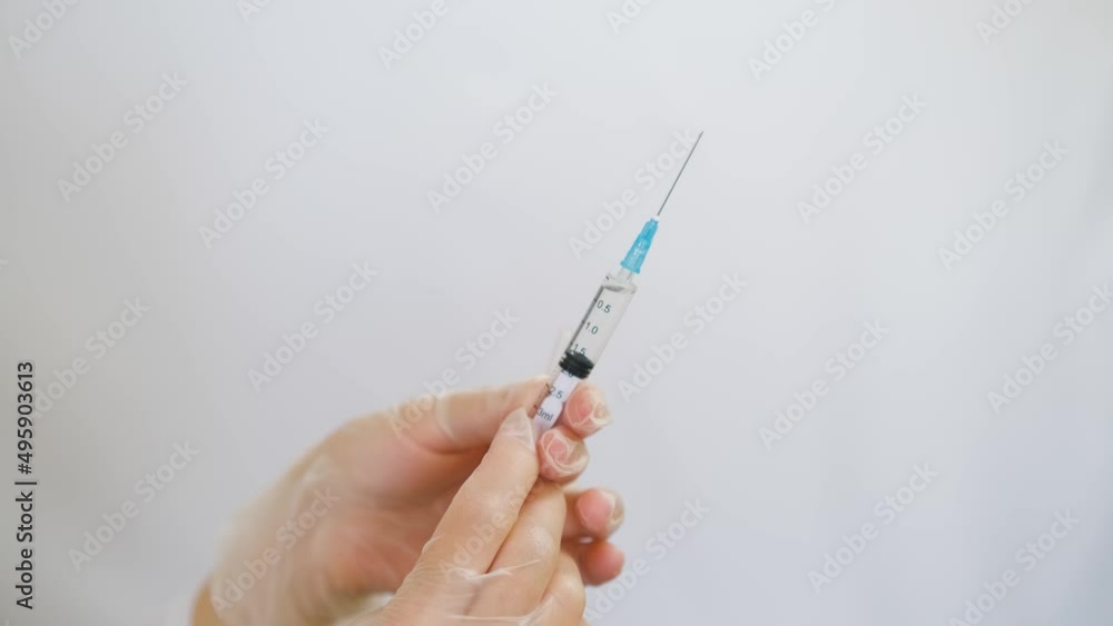 The doctor holds in his hands a medical syringe with medicine before an injection. White background. The doctor holds in his hands a medical syringe with medicine before an injection. White background.