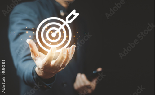 Businessman holding virtual dartboard and arrow with copy space for setup business objective target concept.