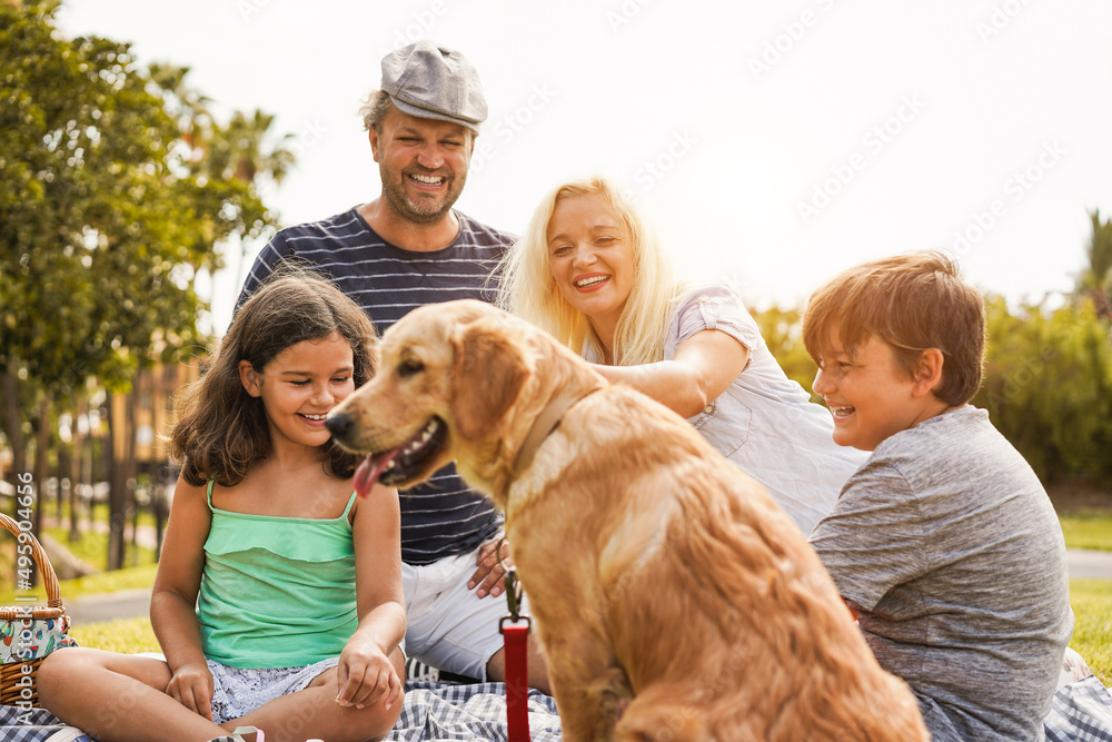Young parents having fun with children and their pet outdoor at park in summer time - Focus on mother face