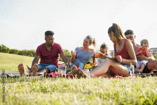 Happy families having fun doing picnic at park outdoor in summer vacation - Focus on center woman face © DisobeyArt
