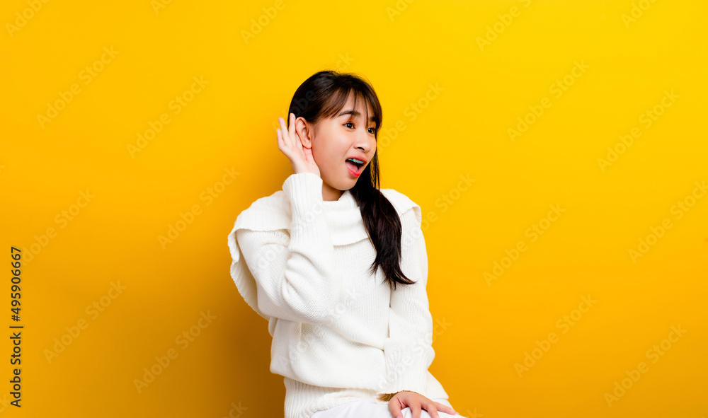 Eavesdropping girl Curious girl in white t-shirt poses alone on orange-yellow wall background studio portrait. concept of people's lifestyle copy space mockup Try to hear you with your hands Eavesdropping girl Curious girl in white t-shirt poses alone on orange-yellow wall background studio portrait. concept of people's lifestyle copy space mockup Try to hear you with your hands