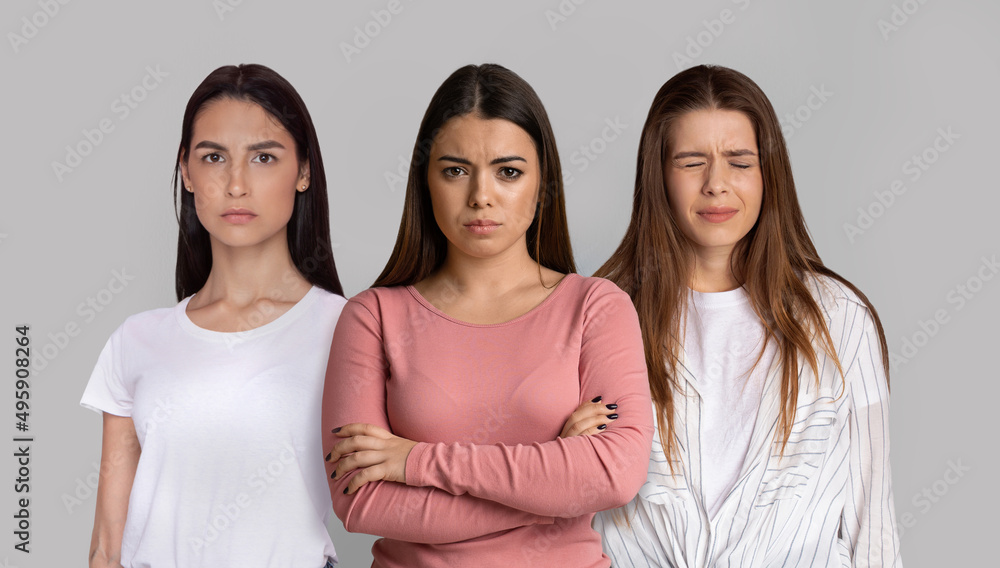 Portrait Of Three Upset Young Women Standing Isolated Over Grey Background Portrait Of Three Upset Young Women Standing Isolated Over Grey Background