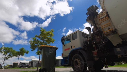 A mechanical arm lifts a wheelie bin and tips rubbish into a garbage truck