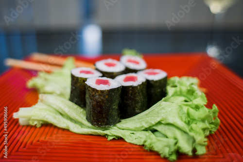 sushi roll with salmon on a plate with salad and chopsticks