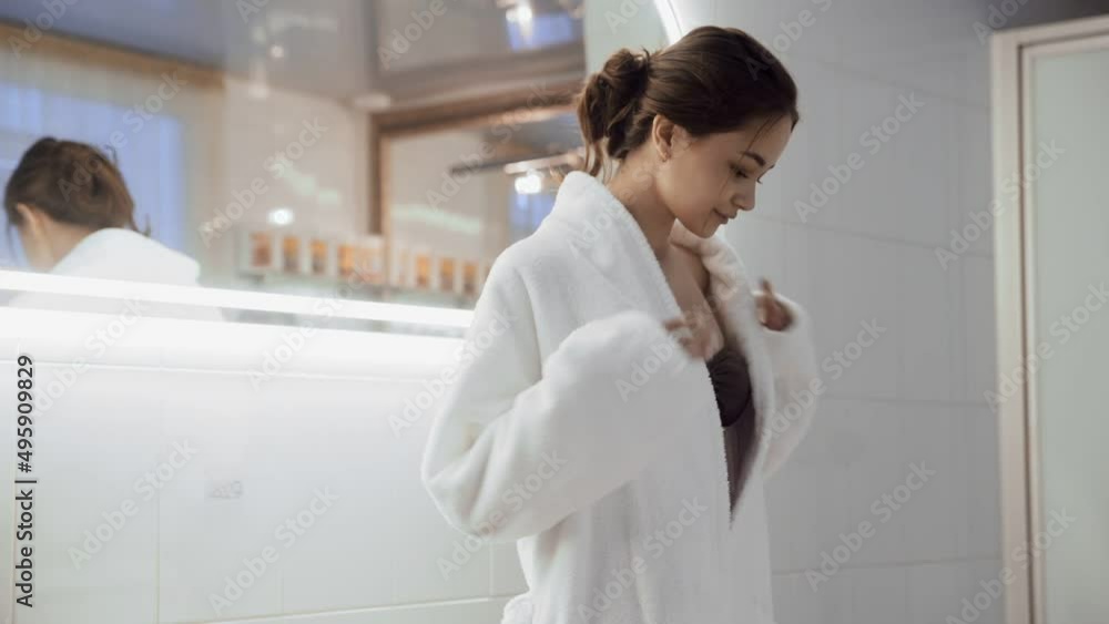 A dark-haired girl takes off a white terry robe to go into the Jacuzzi bath. The concept of a healthy lifestyle and body care. A dark-haired girl takes off a white terry robe to go into the Jacuzzi bath. The concept of a healthy lifestyle and body care.