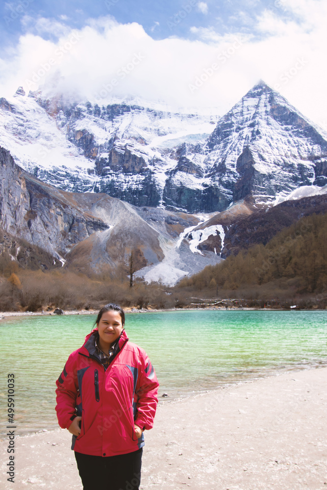 Beautiful traveler woman relaxing meditation with serene view mountains and lake landscape in the morning look at camera. Travel lifestyle hiking summer vacations outdoor concept. Beautiful traveler woman relaxing meditation with serene view mountains and lake landscape in the morning look at camera. Travel lifestyle hiking summer vacations outdoor concept.