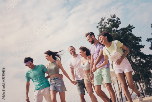Photo of sweet adorable young six friends wear casual clothes smiling holding arms walking laughing outside countryside