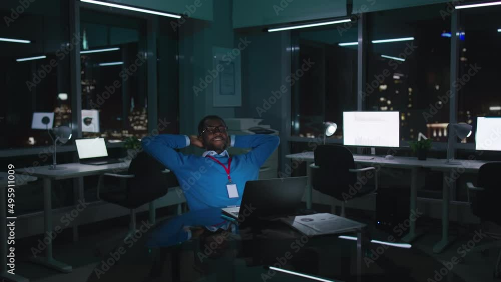 Happy African-American businessman relax and smile working late in modern office in night city Happy African-American businessman relax and smile working late in modern office in night city