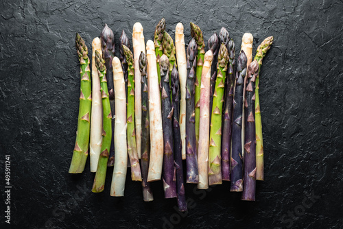 Green, purple and white asparagus sprouts on black board top view flat lay. Food photography