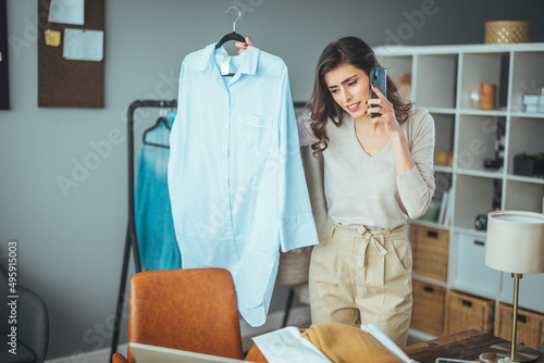 Woman online seller confirming orders from customer on the phone. E-commerce business owner looking at the papers and talking on phone