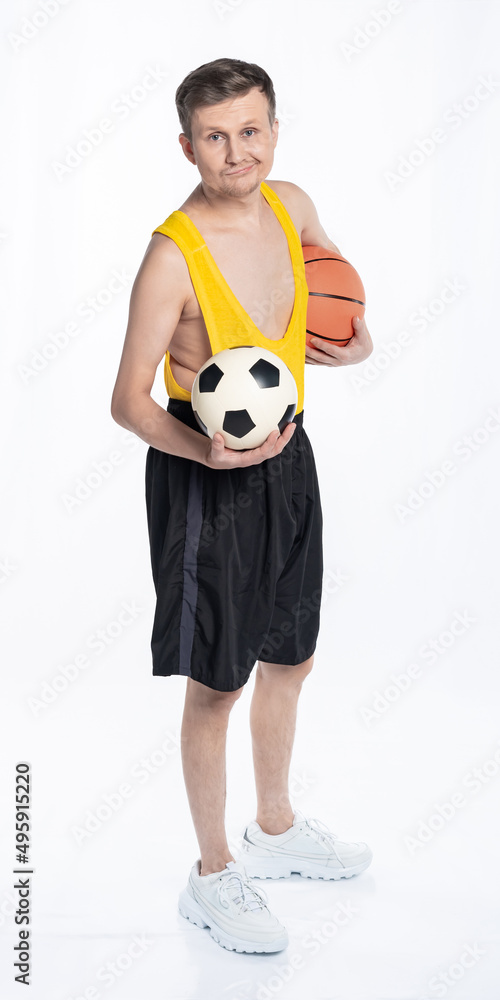 fitness man with a lean body, an athlete in black shorts and a yellow t-shirt with soccer and basketball balls. The concept of sports motivation for training. fitness man with a lean body, an athlete in black shorts and a yellow t-shirt with soccer and basketball balls. The concept of sports motivation for training.