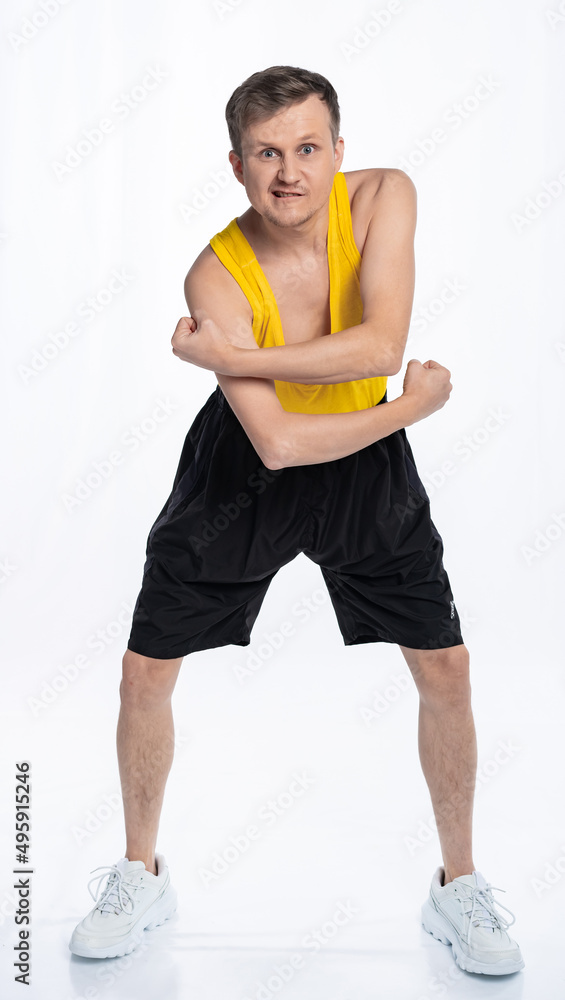 fitness man with a thin body, an athlete in black shorts and a yellow t-shirt clenched his fists and strained his biceps. The concept of sports motivation for training. fitness man with a thin body, an athlete in black shorts and a yellow t-shirt clenched his fists and strained his biceps. The concept of sports motivation for training.