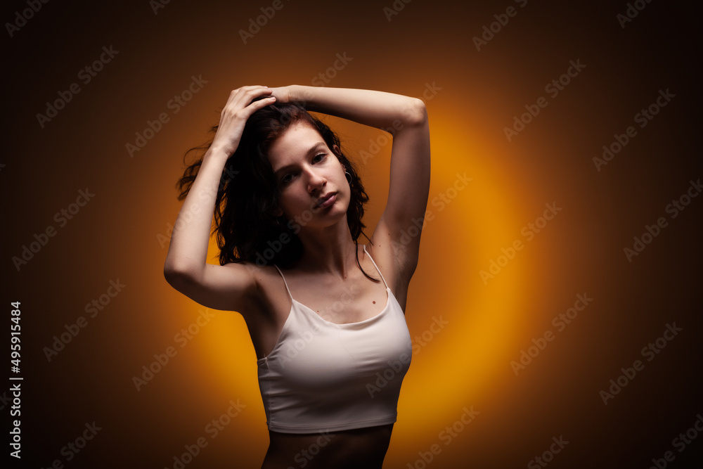Beautiful teenage girl studio portrait on neon orange colored background.. Beautiful teenage girl studio portrait on neon orange colored background..