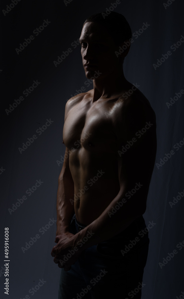 muscular silhouette black background. athletic young man. Black and white dark contrast photo of fitness muscular arms and chest. strong athletic man.