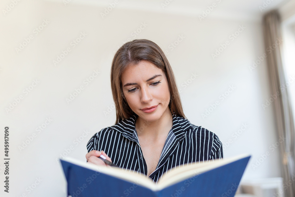 Young beautiful woman holding book, University student studying, learning language. leisure, literature and people concept - smiling woman reading book at home Young beautiful woman holding book, University student studying, learning language. leisure, literature and people concept - smiling woman reading book at home