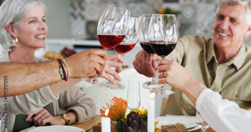 Heres to friends who feel like family. Shot of two happy couples sitting down for lunch and toasting with wine glasses at home. photo