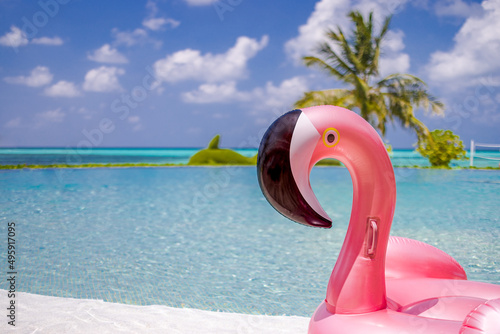 Summer swimming pool with inflatable pink flamingo, luxury resort hotel poolside. Happy blue cloudy sky, tropical paradise island infinity pool sea view. Vacation, holiday fun landscape. Relax leisure © icemanphotos