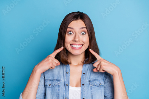 Photo of impressed funny woman wear jeans shirt pointing fingers teeth isolated blue color background photo