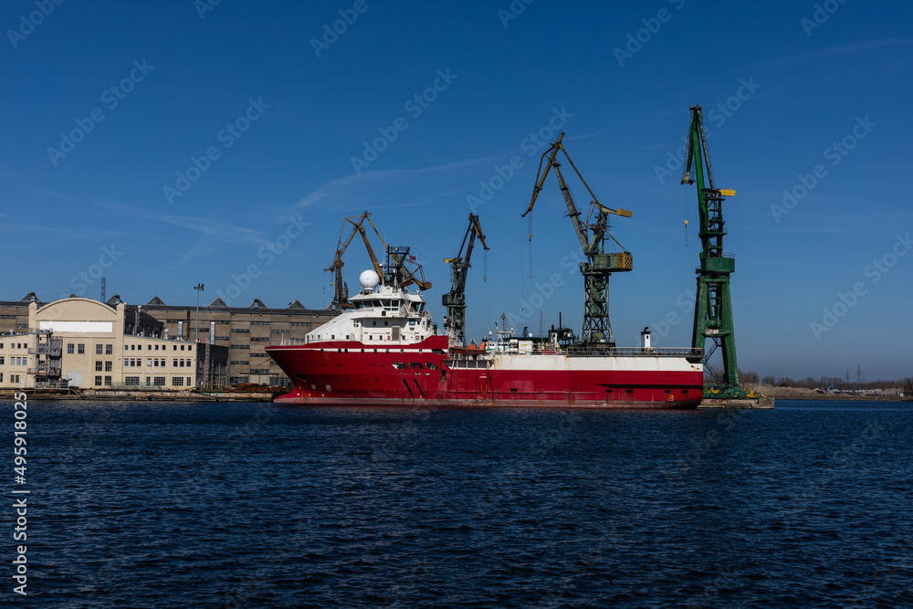 Red ship with port cranes in the background 