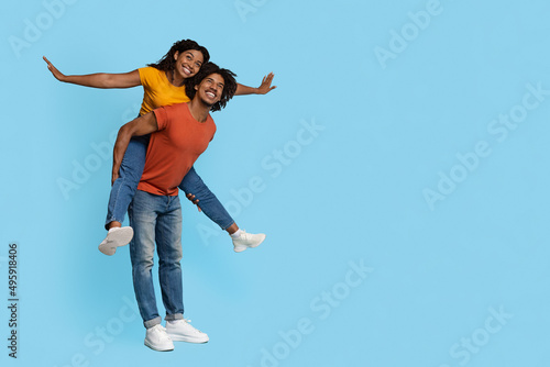 Cheerful black guy piggybacking his happy girlfriend