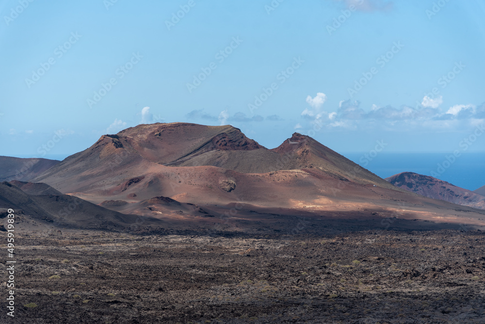 Impresionante paisaje volcánico con un gran volcán inactivo en el Parque Nacional de Timanfaya en Lanzarote, Islas Canarias, durante un día soleado con el cielo azul despejado. Recursos naturales 