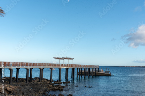 Paisaje costero en Lanzarote Islas Canarias, Muelle la Garita en Arrieta que se adentra en el mar turquesa durante un día de verano soleado y con el cielo despejado. Recursos turísticos naturales. photo