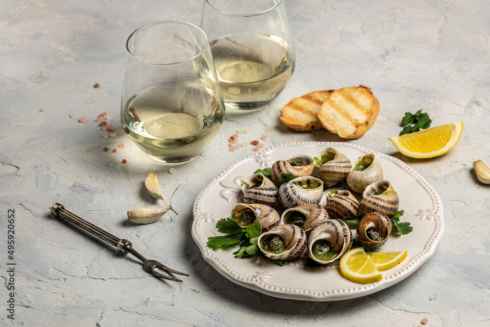 Escargots de Bourgogne or Snails with herbs, butter, garlic on metal plate with forks. wine glass. gourmet food. Restaurant menu, dieting, cookbook recipe Escargots de Bourgogne or Snails with herbs, butter, garlic on metal plate with forks. wine glass. gourmet food. Restaurant menu, dieting, cookbook recipe