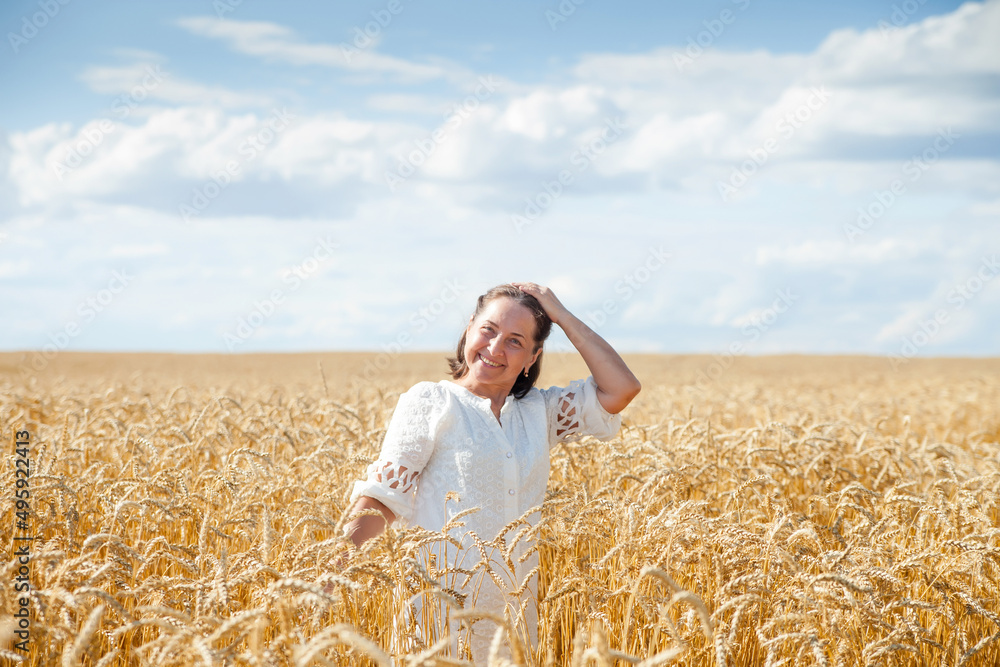 Elderly woman in white walking through wheat field. Elderly woman in white walking through wheat field.