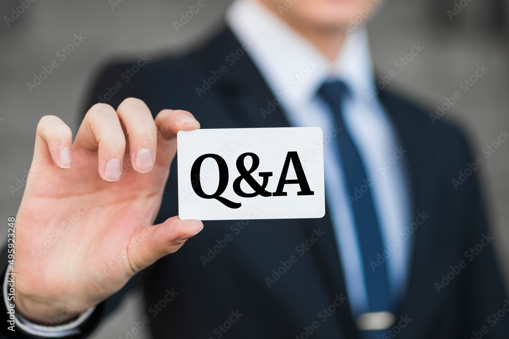 Close-up of man's hand holding and showing visiting card with Q and A word on it. Close-up of man's hand holding and showing visiting card with Q and A word on it.