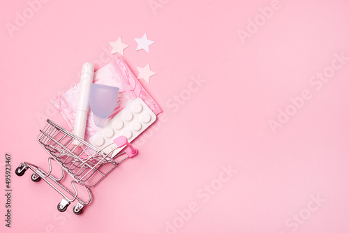 Shopping Cart with Menstruation Period Accessories on Pink Background Sanitary Pads Tampons Menstrual Cup and Pills Horizontal Copy Space