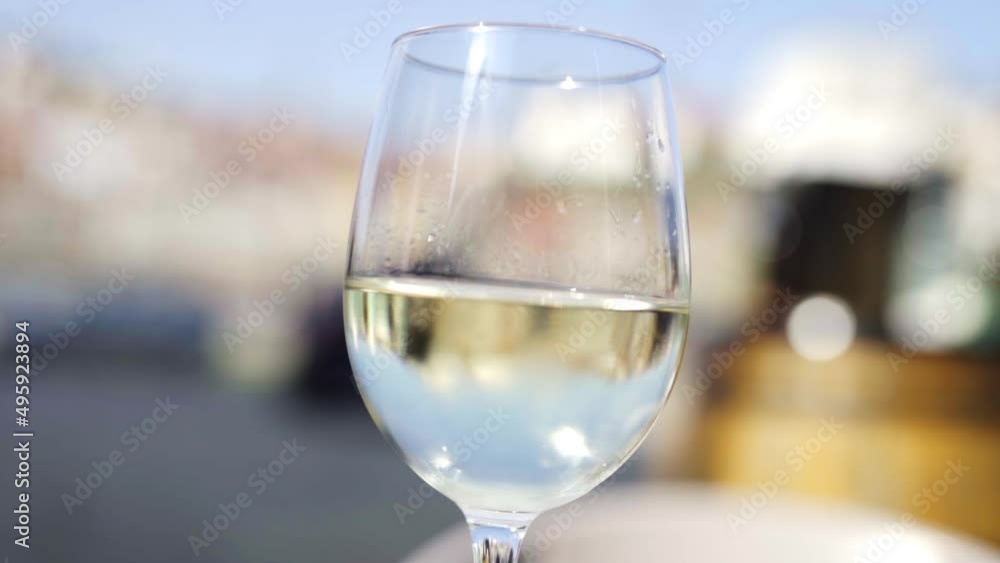 Close up of delicious traditional glass of white porto wine local product of the oporto city of Portugal, blurred cityscape in background Close up of delicious traditional glass of white porto wine local product of the oporto city of Portugal, blurred cityscape in background