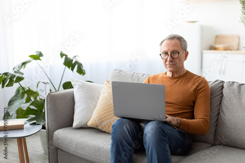 Confident casual mature man using laptop at home © Prostock-studio