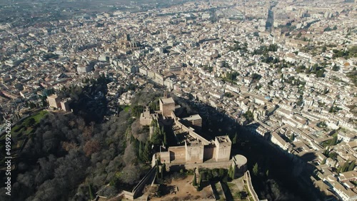Drone flying over Charles V Palace inside Alhambra citadel with cityscape in background, Granada in Spain. Aerial backward
