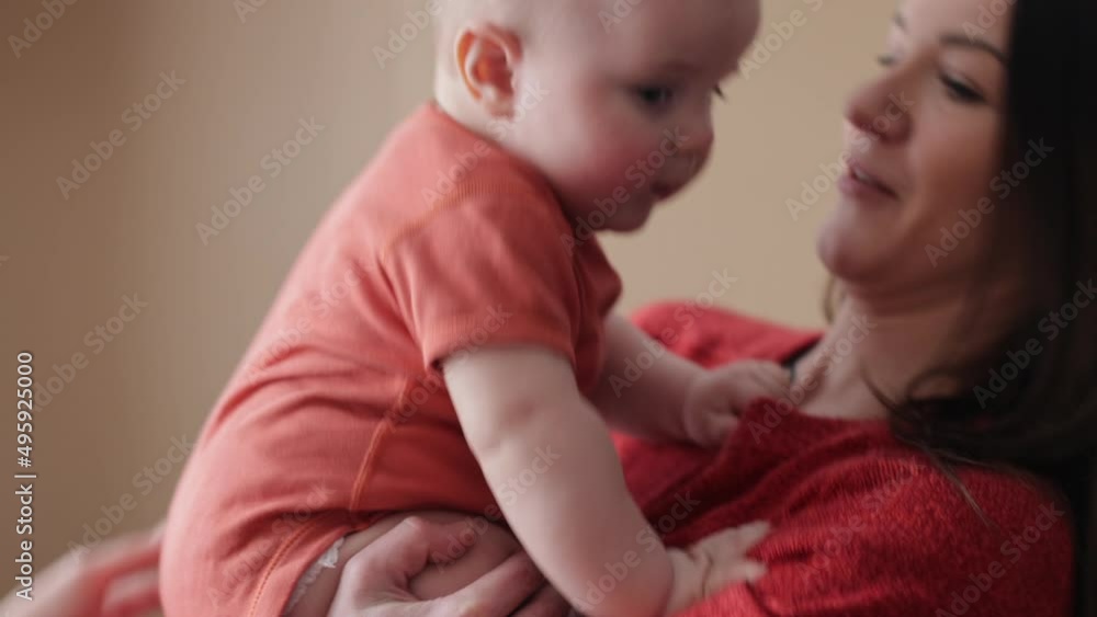 Young cheerful woman playing with her infant bay. Mother spending time with her baby. Motherhood Young cheerful woman playing with her infant bay. Mother spending time with her baby. Motherhood