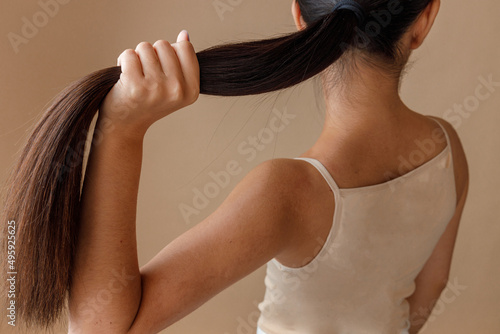 Brunette young woman holding her ponytail in studio photo