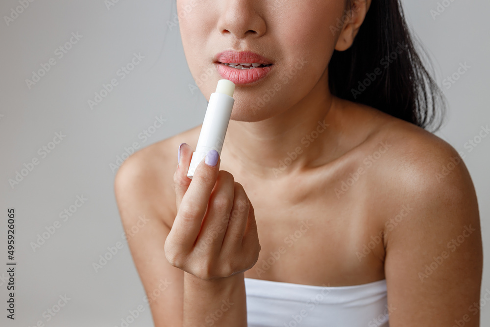Asian young woman applying hygienic lipstick in studio Asian young woman applying hygienic lipstick in studio