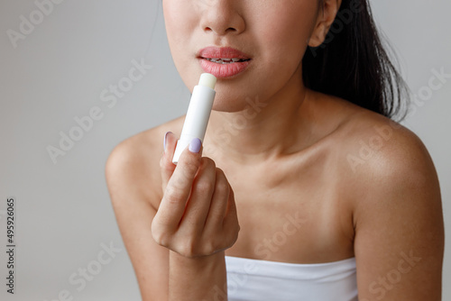 Asian young woman applying hygienic lipstick in studio