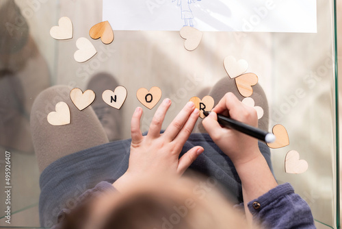 Faceless kid writing phrase on hearts