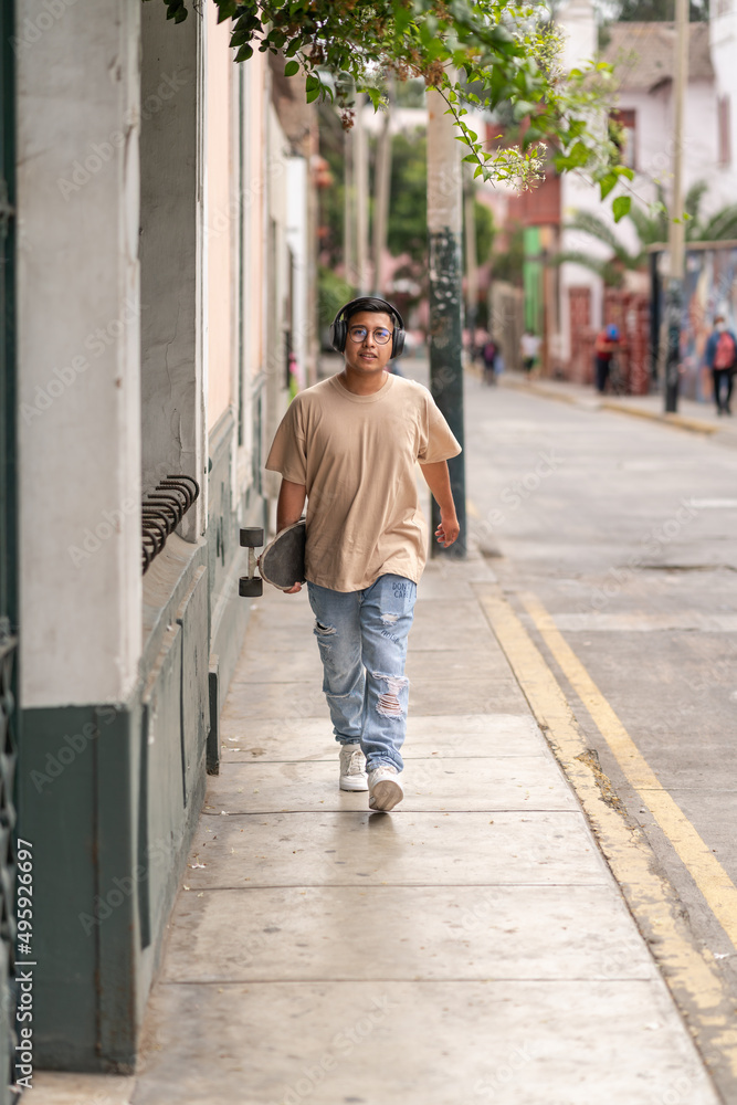 Ethnic skater carrying skateboard on street Ethnic skater carrying skateboard on street