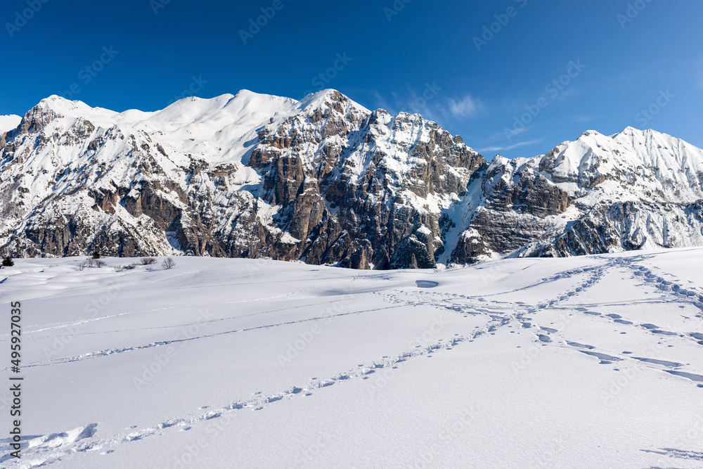 Obraz premium Snow capped mountain peaks in Italian Alps. Mountain range of Monte Carega (Small Dolomites) in winter, and Lessinia Plateau (Altopiano della Lessinia). Veneto and Trentino Alto Adige, Italy, Europe.