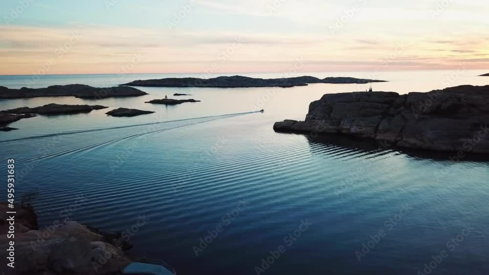Drone flying towards motorboat over open waters during sunset.