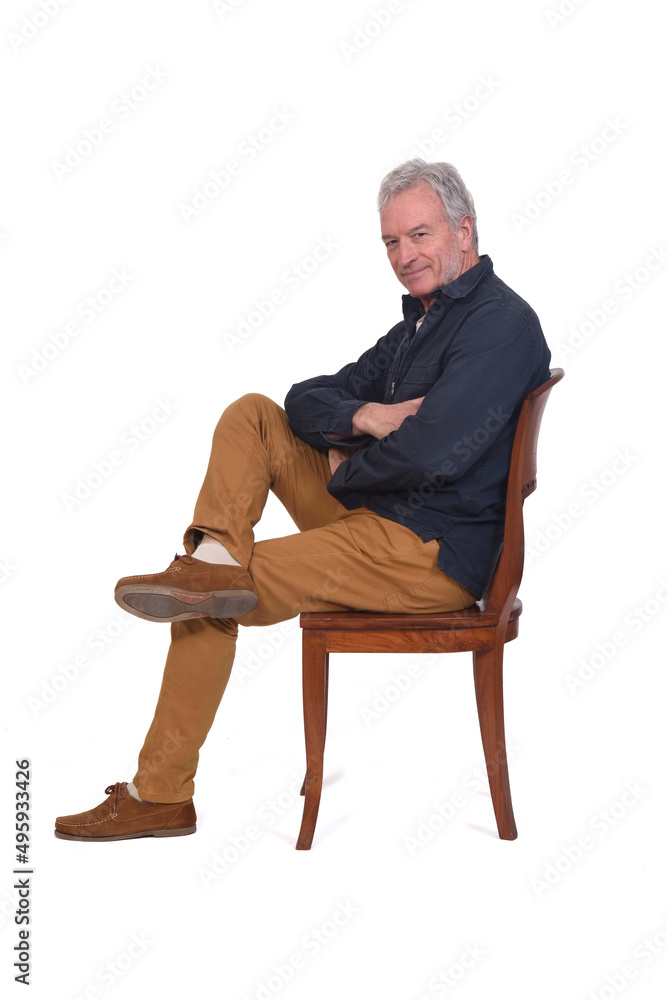 side view of a man sitting on chair looking at camera and legs and arms crossed on white background