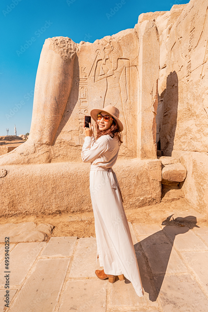 A blogger girl takes photos in the ruins of the grandiose Karnak temple in the ancient city of Luxor in Egypt