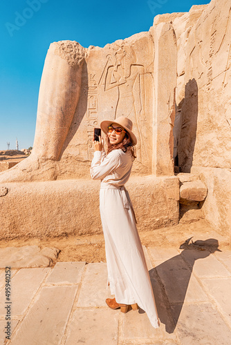 A blogger girl takes photos in the ruins of the grandiose Karnak temple in the ancient city of Luxor in Egypt photo