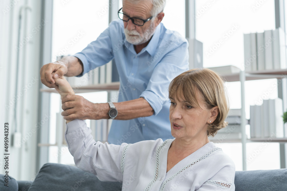 Obraz premium Health, body muscles stiff problem of senior couple, caucasians mature, adult retired husband, wife pain with back pain ache holding massaging rubbing shoulder hurt or sore, painful sitting on sofa.