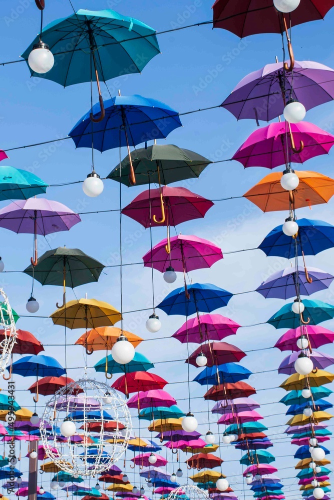 Obraz premium Colored umbrellas on a blue sky background in sunny weather