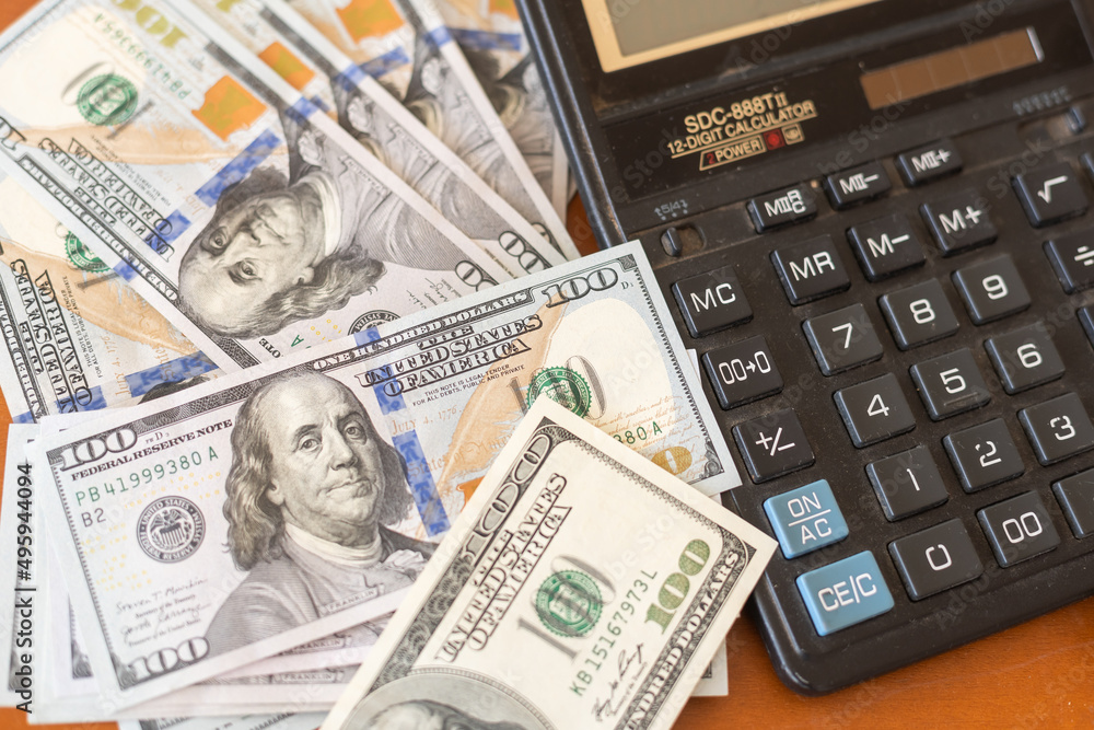 Calculator and 100 dollars on wooden table. Calculator and 100 dollars on wooden table.