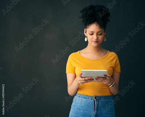 This is quite a read.... Shot of a young woman holding a digital tablet while posing against a grey background.